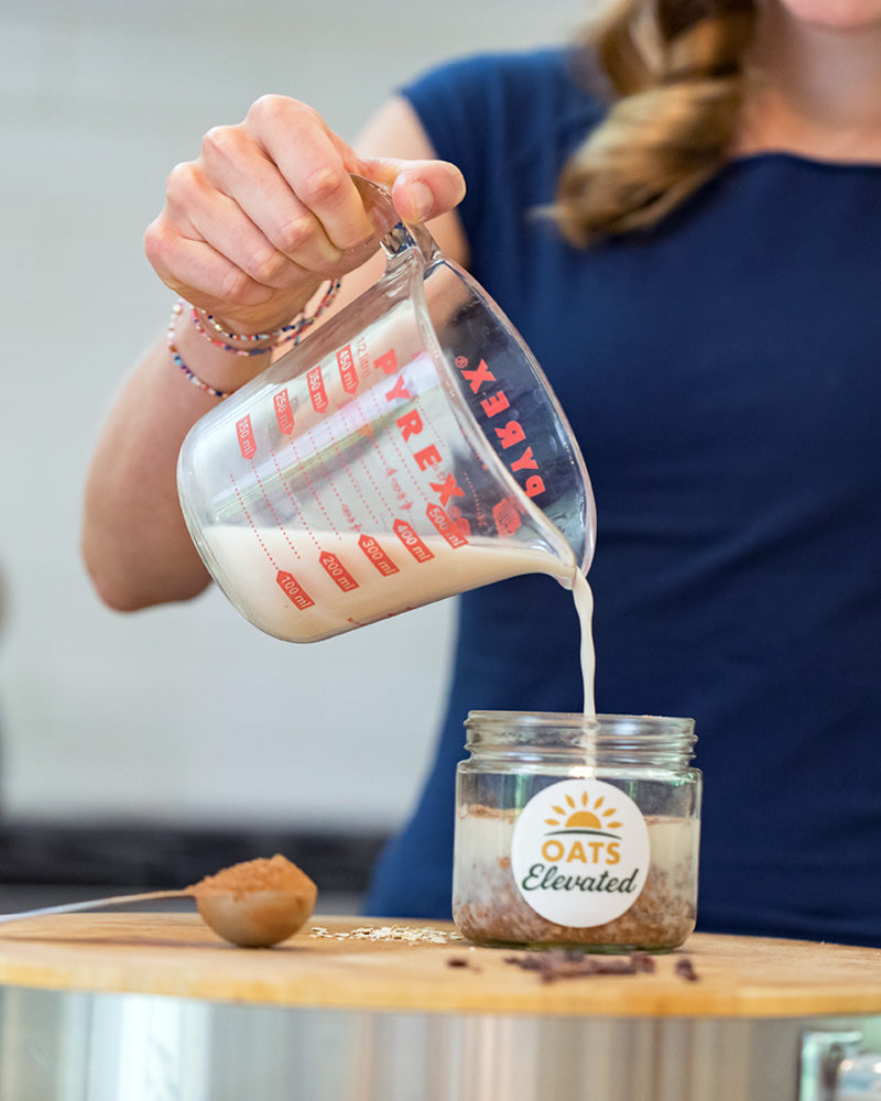 Brooke Sweeney demonstrating how to prepare overnight oats – step 2, add milk or a alt-milk, close, shake, and refrigerate at least an hour.  